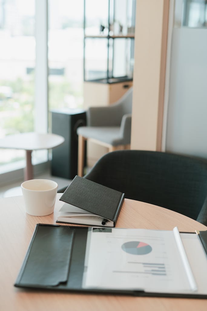 A modern office setting featuring a notebook, coffee cup, and documents on a wooden desk.